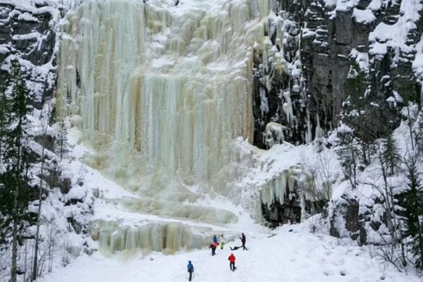 Pessoas na neve em frente a cachoeiras congeladas