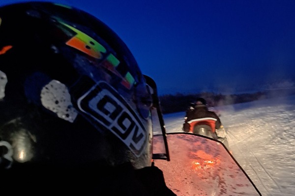 Dois snowmobiles em uma estrada com neve à noite