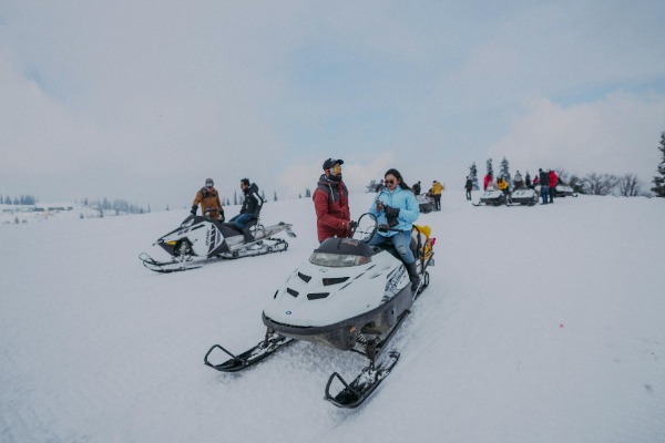 Pessoas com snowmobiles estacionados na neve