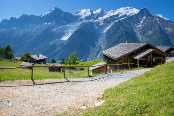 Casas de madeira na montanha em frente ao caminho nevado e à montanha