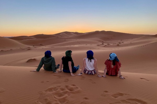 Pôr do sol nas dunas de Erg Chebbi Viajantes contemplando o pôr do sol entre as dunas de Erg Chebbi, em Merzouga