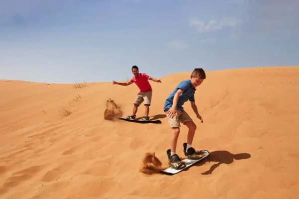 Sandboard nas dunas de Erg Chebbi Turistas praticando sandboard nas dunas de Erg Chebbi durante a excursão ao deserto de Merzouga