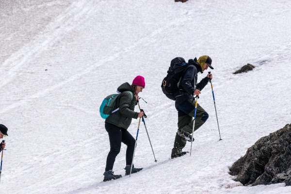 duas pessoas com bastões de trekking subindo no gelo