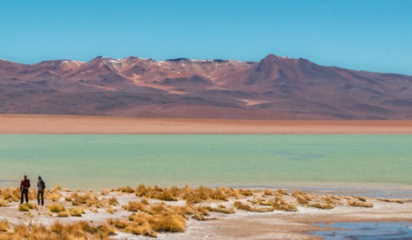 Viajantes caminhando pelas lagoas altiplânicas em um dia ensolarado