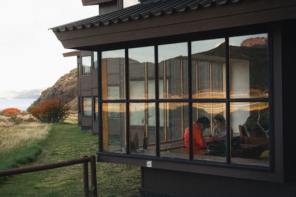 Exterior do Refúgio Paine Grande em Torres del Paine, com caminhantes descansando em seu interior e vistas da paisagem patagônica.
