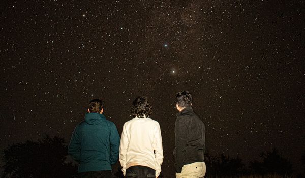 Três meninos olhando para o céu estrelado