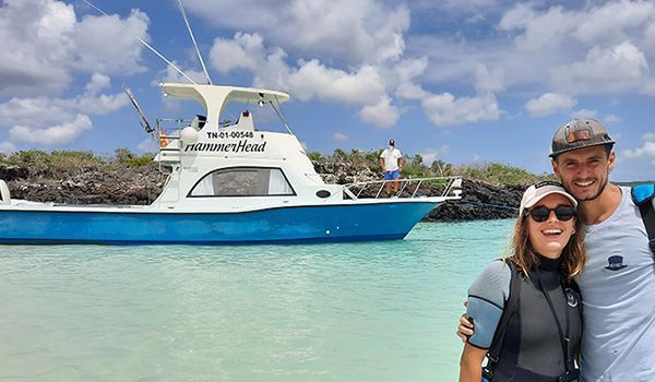 casal em frente a um barco em Puerto Baquerizo Moreno san cristobal