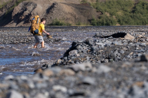 Menino com mochila atravessando o rio Brattháls