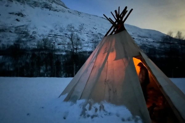 Samische Hütte mit einer Person in einer verschneiten Landschaft