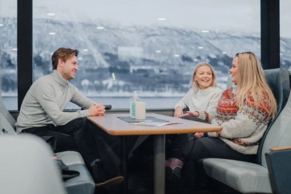 Arktische Fjord-Kreuzfahrt Menschen in warmer Kleidung, die vom Schiff aus die schneebedeckten Berge der arktischen Fjorde betrachten