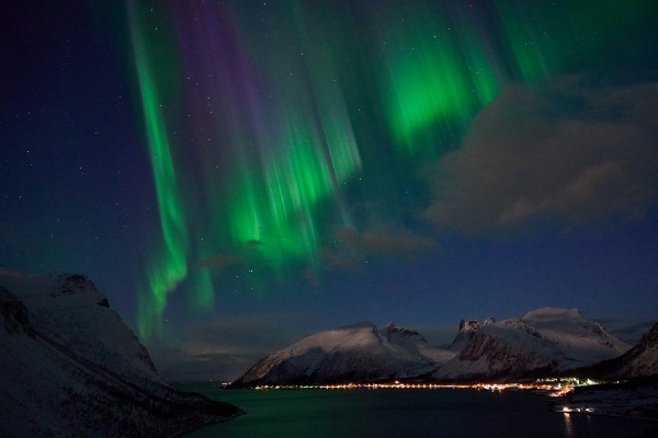 Polarlicht über den nordnorwegischen Fjorden Grünes und violettes Polarlicht erleuchtet den Himmel über einem verschneiten Fjord bei Tromsø