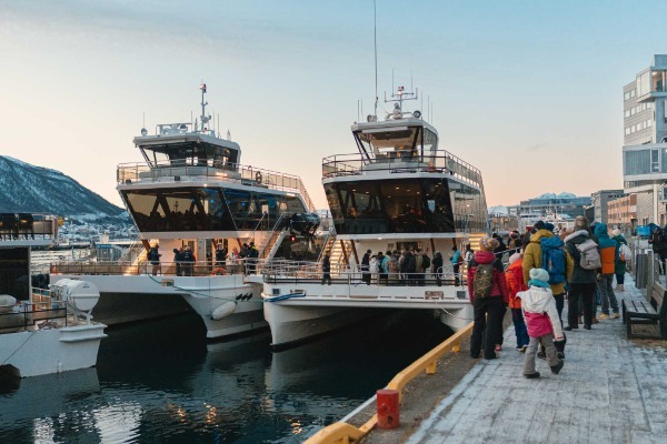Einschiffung in Tromsø zur Walfangtour Reisende besteigen das Hybrid-Elektroboot im Hafen von Tromsø zu Beginn der Tour.