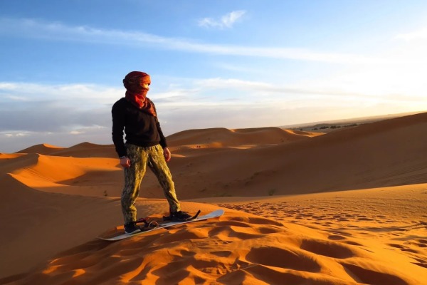 Sandboarding in den Dünen von Erg Chebbi Ein Reisender beim Sandboarden in den Dünen von Erg Chebbi in Merzouga