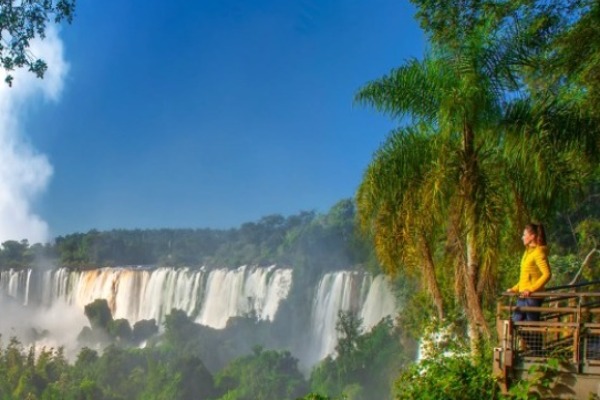 Frau betrachtet die Iguassu-Fälle von der brasilianischen Seite aus von einem Steg aus