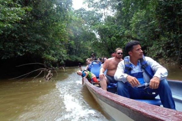Eine Gruppe von Reisenden paddelt in Begleitung eines Reiseleiters in einem Kanu den Cuyabeno-Fluss hinunter
