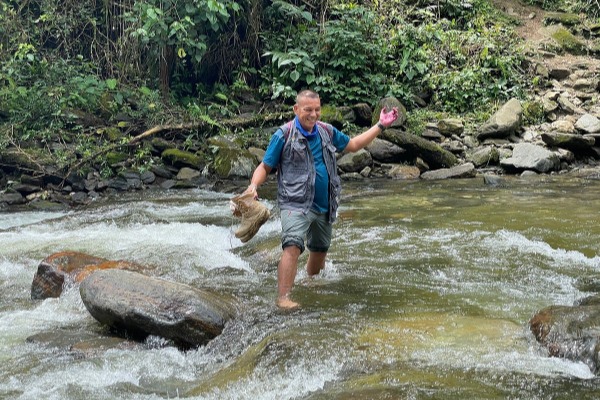 Flussüberquerung während des Trekkings Führer, der während des Ciudad Perdida-Trekkings barfuß den Fluss überquert Kolumbien