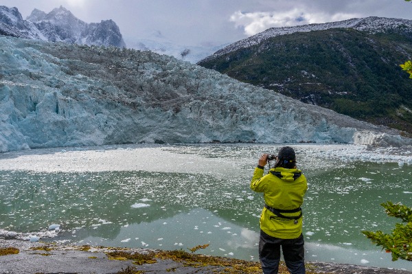 Pía, the glacier woman A woman with her back to the camera photographs the Pía Glacier