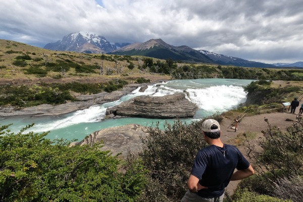 Man admiring the Paine Waterfall during the shuttle bus tour
