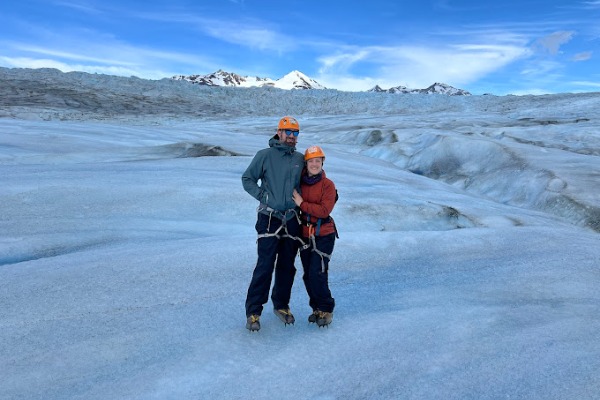 couple embraced walking on grey glacier ice