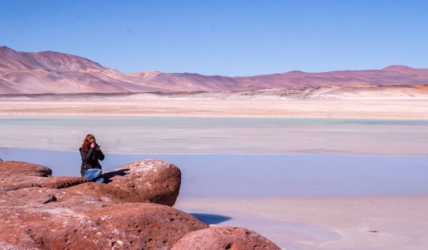 girl sitting and taking pictures of the reddish stones