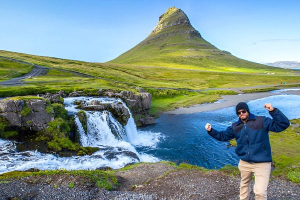 Kirkjufell Mountain and Kirkjufellfoss Waterfall Man in front of the glacial landscape of Kirkjufell Mountain and Kirkjufellfoss Waterfall