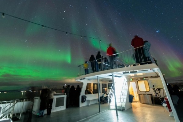 people on the deck of the catamaran watching the northern lights