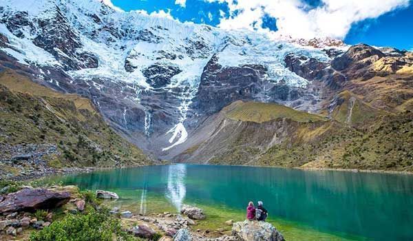 couple sitting on their backs in the humantay lagoon on the first day of the salkantay trek