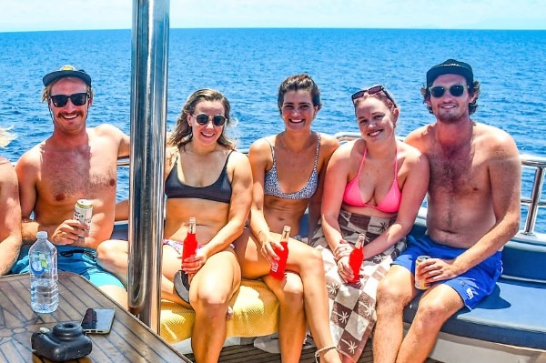 Pasajeros relajándose en la cubierta durante el tour en semisumergible por la Barrera de Coral desde Cairns Grupo de jóvenes disfrutando de bebidas al aire libre en la cubierta del barco en aguas de Cairns.