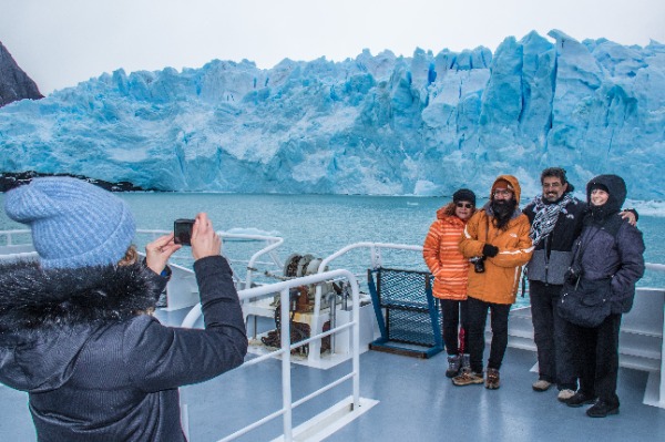 turistas tomando foto desde barco frente al perito moreno