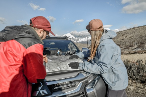 Planificación de la ruta con mapa sobre el capó en el Torres del Paine Puma Tour – Safari Privado Dos personas revisando un mapa desplegado sobre el capó de un todoterreno en pleno campo.