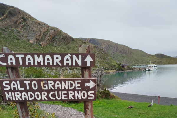 Señal hacia el catamarán en Paine Grande con barco en el Lago Pehoé al fondo
