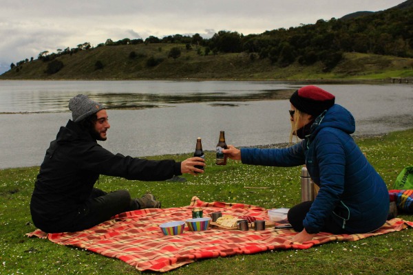 brindis con cerveza artesanal y picoteo pareja tomando un picoteo sobre un mantel y brindando con cerveza artesanal en Puerto Eugenia