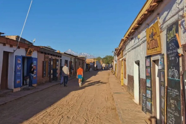 personas caminando por una calle de San Pedro de Atacama llena de tiendas locales