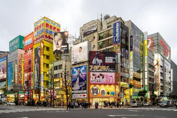 Avenida principal de Akihabara rodeada de edificios con carteles publicitarios de anime y cultura pop.