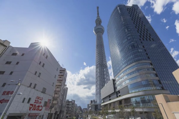 Imponente torre Tokyo Skytree elevándose junto a rascacielos modernos bajo un cielo azul despejado.