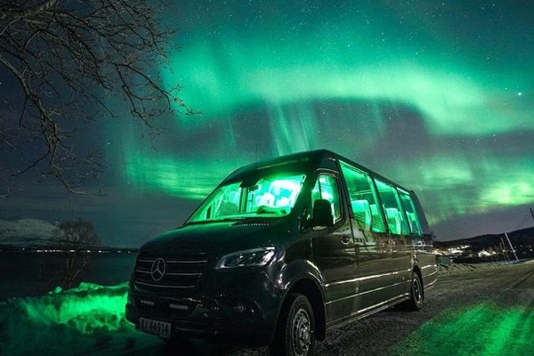 Minibús climatizado con techo de cristal y viajeros a bordo, durante una excursión en busca de auroras boreales desde Tromsø