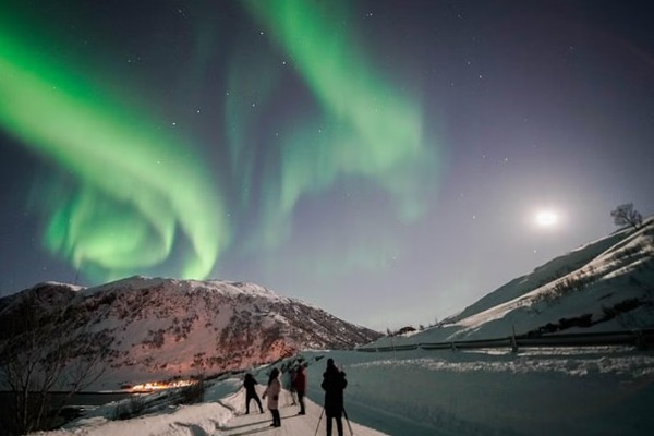 Guía enseñando a un viajero a configurar su cámara para fotografiar la aurora boreal durante el tour en Tromsø