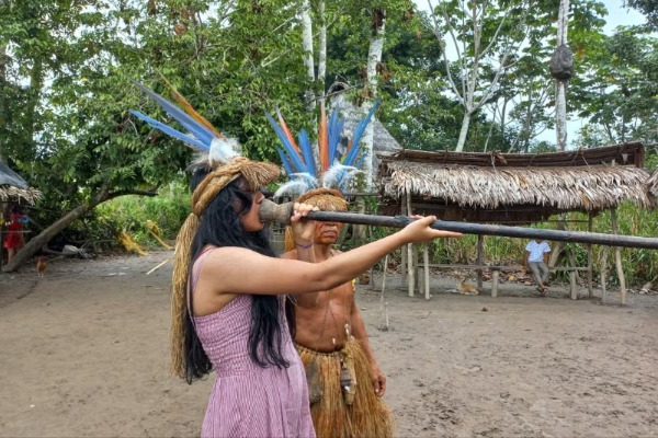 comunidad nativa indigena al lado de una chica enseñandole como tocar los instrumentos tipicos