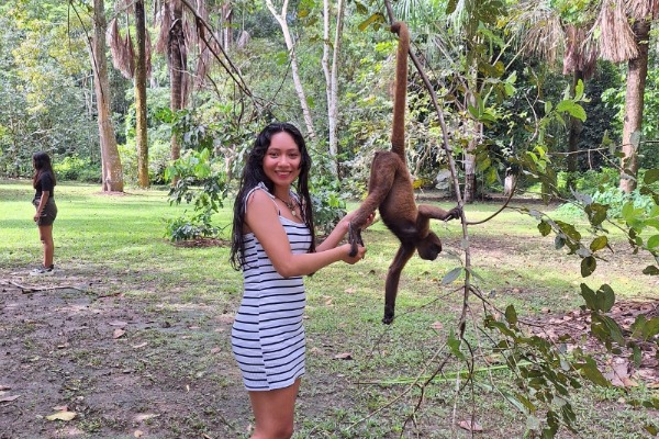Visita a la Isla de los Monos una chica tocando a un mono colgado de una rama en la isla de los monos de iquitos