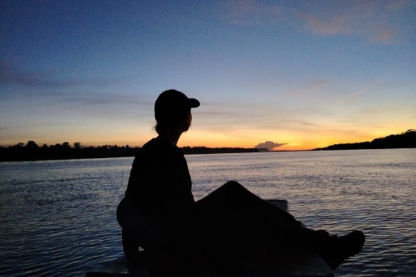 Atardecer en el río Amazonas desde una canoa Persona sentada contemplando el atardecer sobre el Amazonas en Iquitos