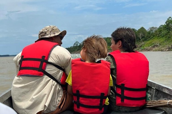 Paseo en bote por el Amazonas en familia Tres personas con chaleco salvavidas navegando por el río Amazonas en un bote