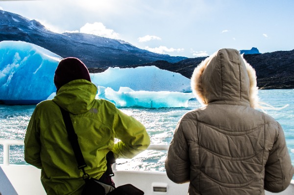 personnes de dos photographiant un iceberg pendant la navigation