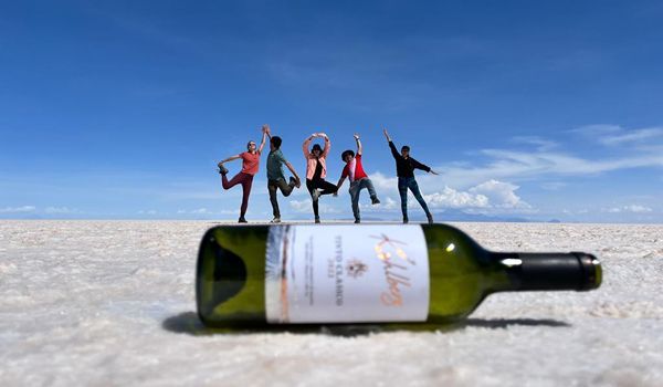 Photo amusante de 5 personnes au dessus d'une bouteille de vin lors d'une excursion dans les salines d'Uyuni