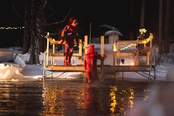deux personnes en combinaison spéciale sur le quai sortant du lac gelé