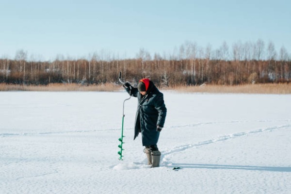 pêche au lac arctique personne faisant un trou dans la glace en Laponie pour pêcher