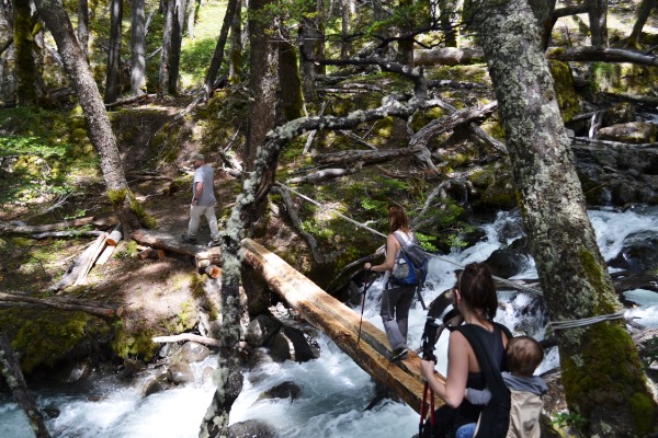 turisti durante il trekking trekking con difficoltà, fiume sullo sfondo e turista con bambino nello zaino