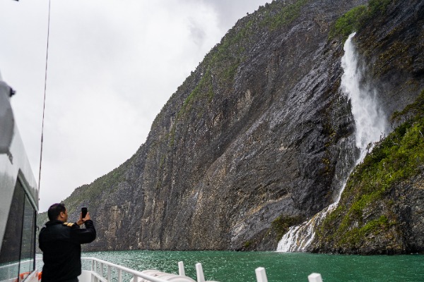 Turista fotografa la cascata nel fiordo di Ultima Esperanza