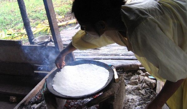 Preparazione del pane di manioca Donna locale che cucina il pane di manioca sul fuoco