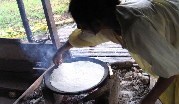 preparazione della manioca donna accovacciata che cucina pane con farina secca di manioca