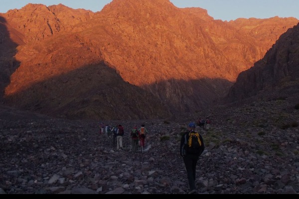 sentiero roccioso lungo il percorso verso il lago Ifni Escalatori che camminano lungo il sentiero verso il lago Ifni durante il giro del Toubkal in Marocco